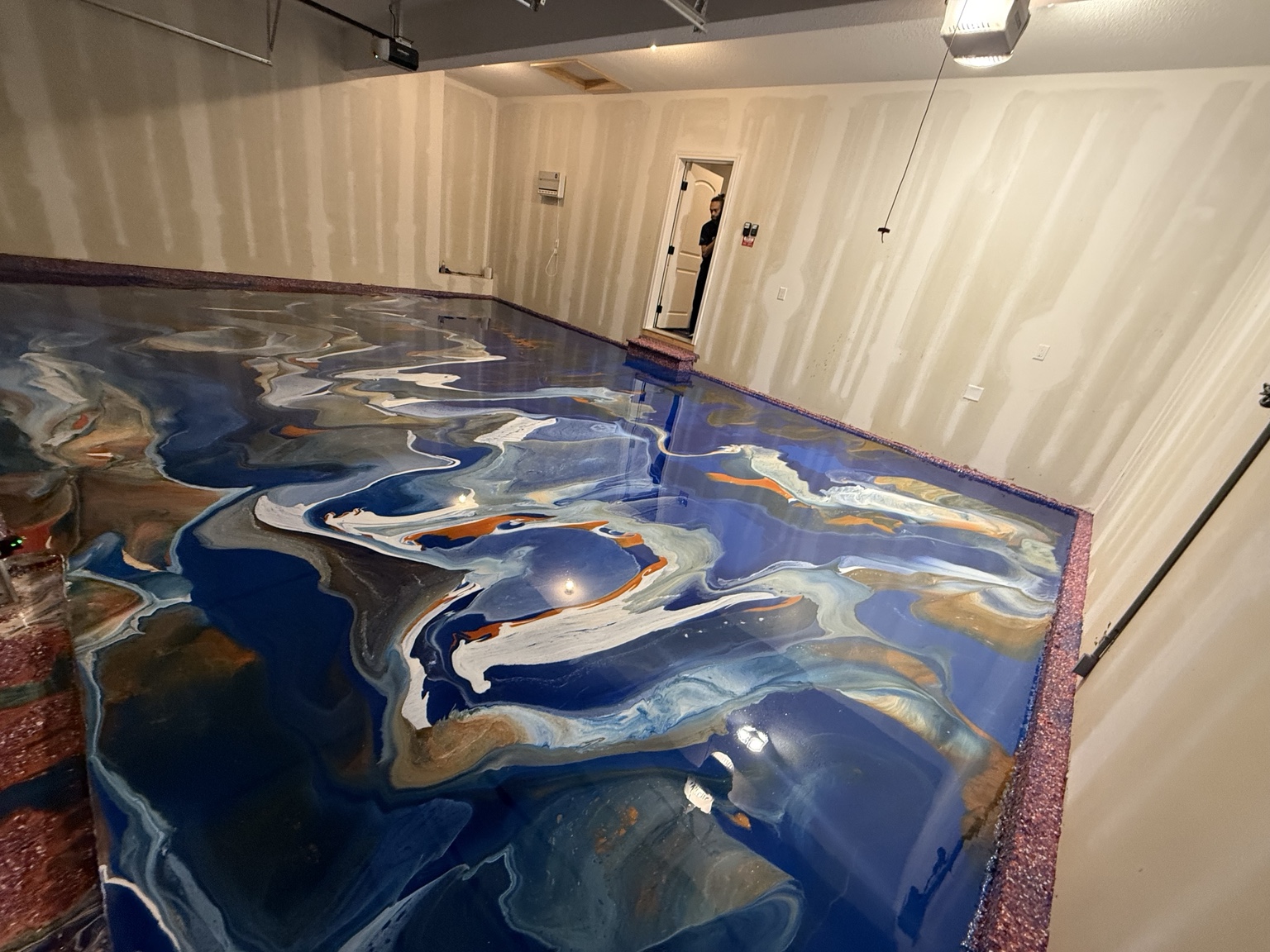 Wide view of a blue metallic garage floor with flowing silver and warm colored accents