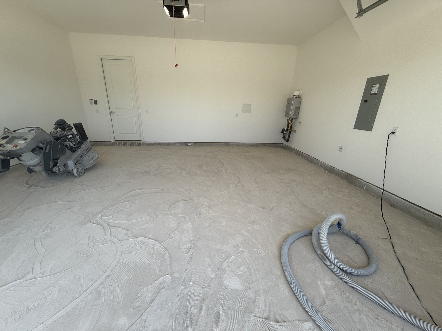Garage concrete during surface preparation, with grinder and vacuum equipment